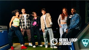 Top Golf Blog feature image - Rebel Loop Studios - Rebel Loop Studios Six diverse young adults pose together on a night set with Rebel Loop Studios logo visible in the foreground, smiling at the camera.