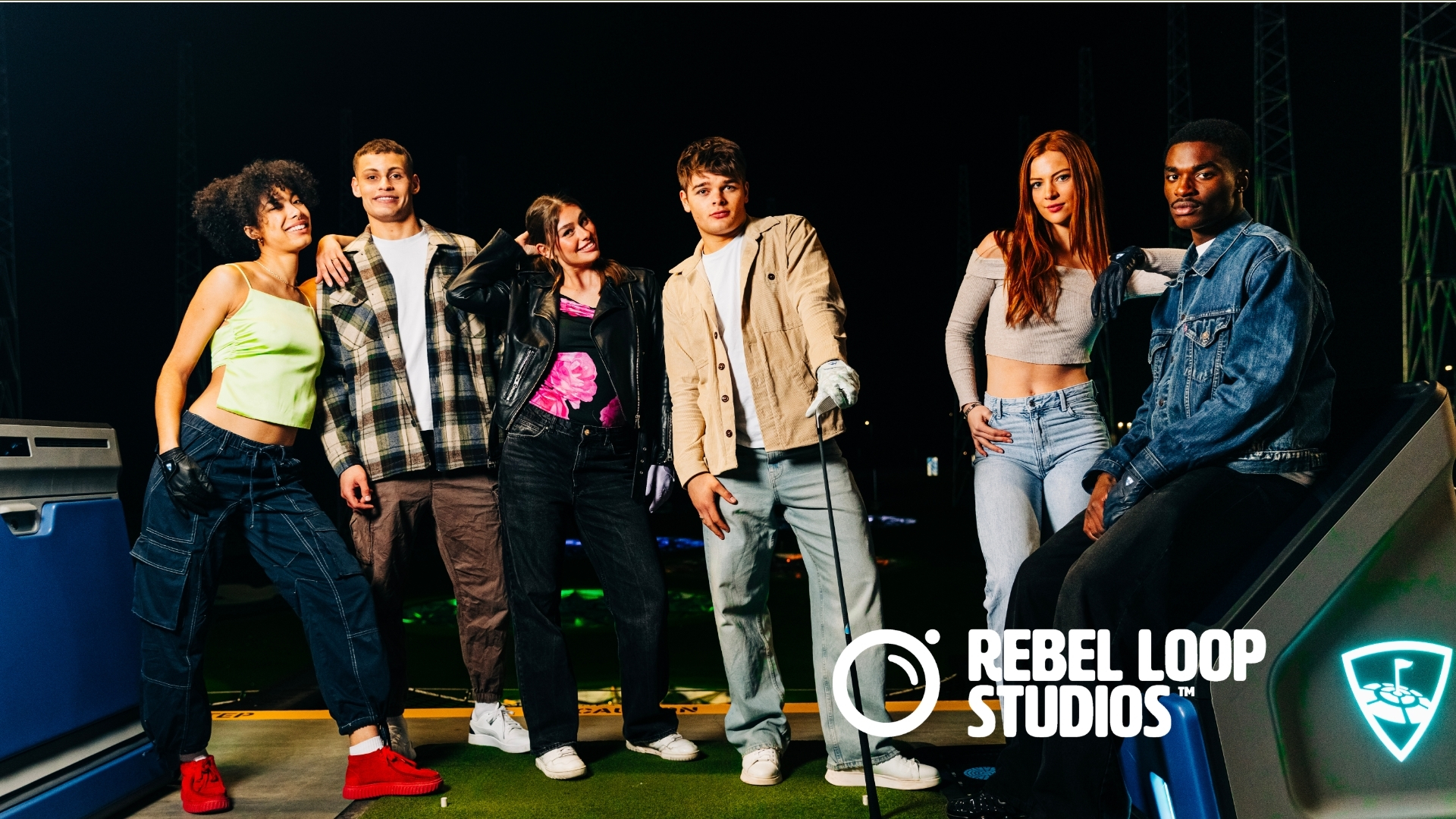 Top Golf Blog feature image - Rebel Loop Studios Six diverse young adults pose together on a night set with Rebel Loop Studios logo visible in the foreground, smiling at the camera.